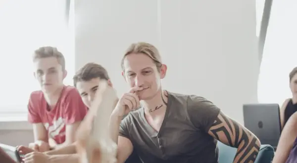 Junge Männer im Gespräch, einer mit Tattoos, vielleicht beim bachelor physiotherapie berufsbegleitend.