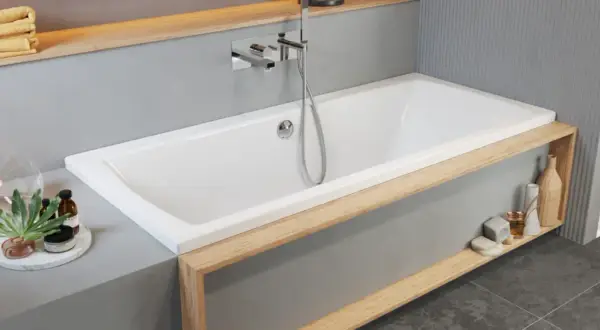 Moderne Badewanne einbauen: Weiße Wanne mit Holzakzenten, Armatur und Handbrause. Dekorative Elemente wie Lampen und Flaschen schmücken die Ablage.