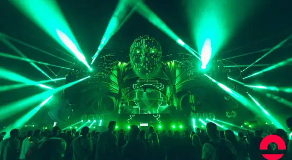 Niesamowita scena z zielonymi światłami i głową z cyframi na Sunrise Festival. Tłum bawi się przy muzyce, czekając na ogłoszenie line-up.