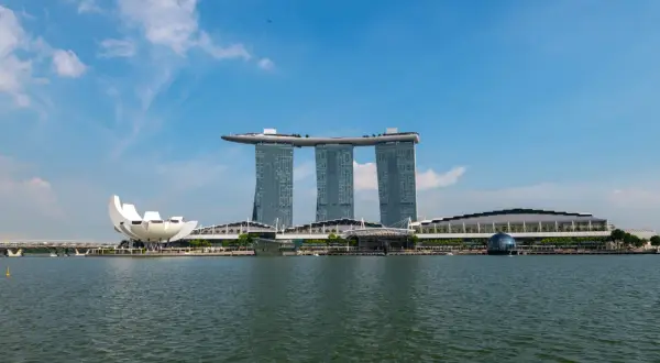 Widok na Marina Bay Sands, gdzie jest Singapur. Woda, nowoczesne budynki i niebieskie niebo.