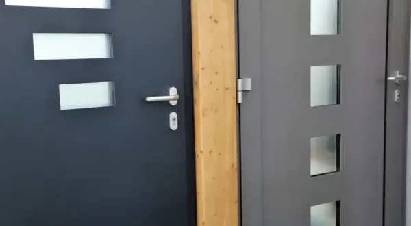 Dwie nowoczesne drzwi wejściowe, ciemnoszare i szare, z przeszkleniami. Dowiedz się, jak uszczelnić drzwi wejściowe, by zapewnić komfort.