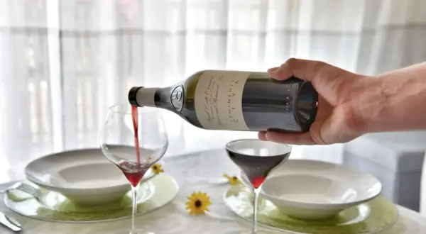 Versando vino rosso nel bicchiere, un gesto che anticipa una cena speciale.