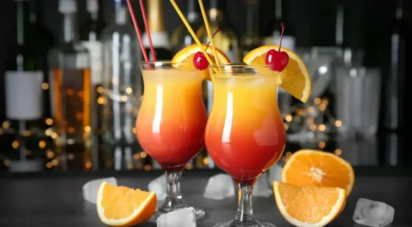 Dwa orzeźwiające drinki z wódką, udekorowane pomarańczą i wiśnią, stoją na barze.