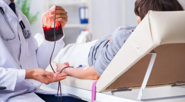 Un médecin prépare une transfusion sanguine pour un patient, une procédure essentielle pour traiter des affections comme la maladie de Biermer.