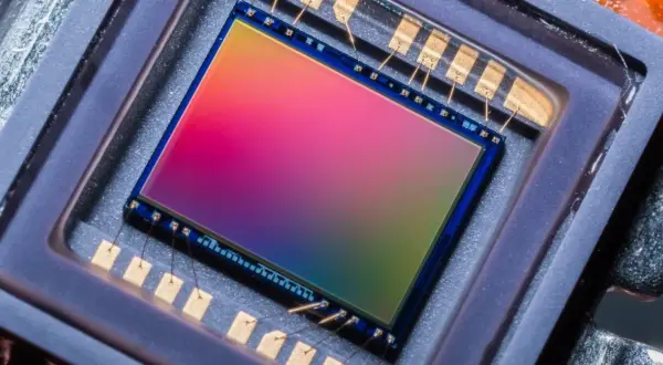 Sensore di immagine 576 megapixel con sfumature arcobaleno, collegato da sottili fili dorati a contatti metallici.