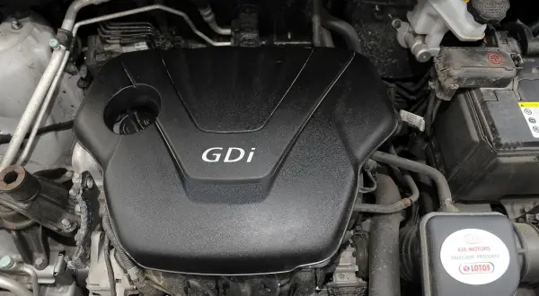 Silnik Kia Sportage GDi, widoczny pod maską, z elementami układu chłodzenia i akumulatorem.