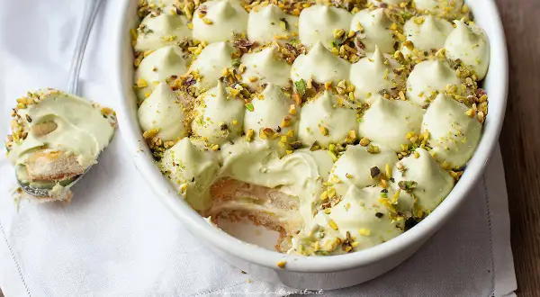 Un cremoso tiramisù al pistacchio, guarnito con granella di pistacchi, pronto per essere gustato.