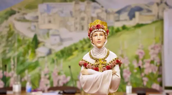 Figurka przedstawia postać z la salette objawienia, ubraną w białe szaty i złotą koronę z róż. Tło to malowidło górskiego krajobrazu.