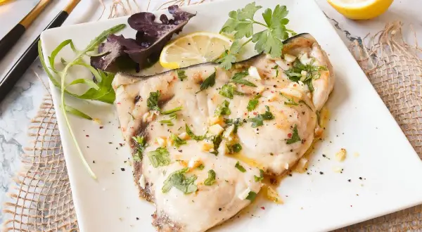 Delicioso emperador a la plancha con ajo, perejil y limón, servido con ensalada.