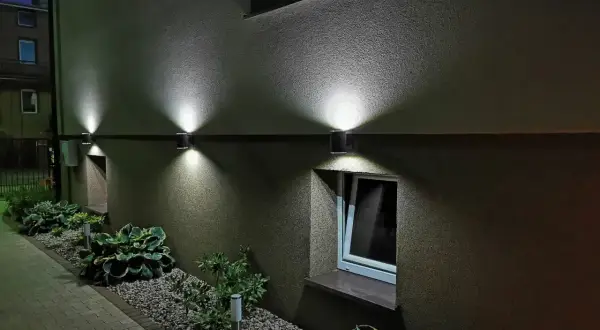 Nowoczesny kinkiet na balkon oświetla ścieżkę i rośliny, tworząc nastrojową atmosferę wieczorem.
