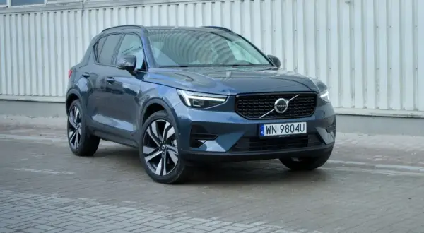 Elegancki, ciemnogranatowy Volvo XC40 2021 z charakterystycznymi światłami LED i felgami, zaparkowany przed budynkiem.