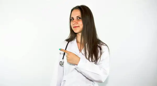 Lekarka w białym kitlu wskazuje palcem, sugerując, że tu jest rozwiązanie, jak Beloderm na problemy skórne.