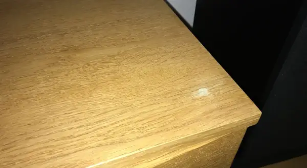 En träyta med tydlig ådring, kanske redo att slipa faner för en jämnare finish. En vit fläck syns på kanten.