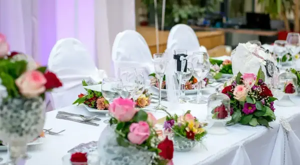Elegancko nakryty stół weselny z bukietami róż i goździków. Idealne pomysły na wesele, pełne romantyzmu i stylu.