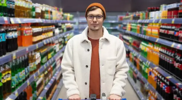 Mężczyzna z wózkiem sklepowym w alejkach pełnych napojów. Branża retail w praktyce, gdzie wybór jest ogromny.