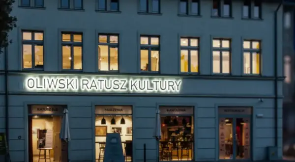 Oświetlony napis "Oliwski Ratusz Kultury" nad wejściami do B&B, Marzeń, Kawiarni i Restauracji.