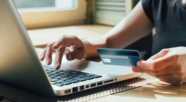 Osoba wpisuje dane karty kredytowej mBank na laptopie, realizując płatność online.