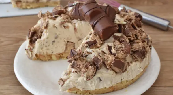Una golosa torta kinder bueno, con crema e pezzi di cioccolato, su un piatto bianco.