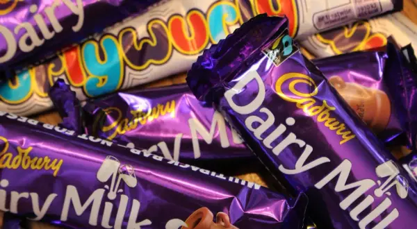 Barras de chocolate Cadbury Dairy Milk y Crunchie, icónicos dulces británicos, apilados en un primer plano.
