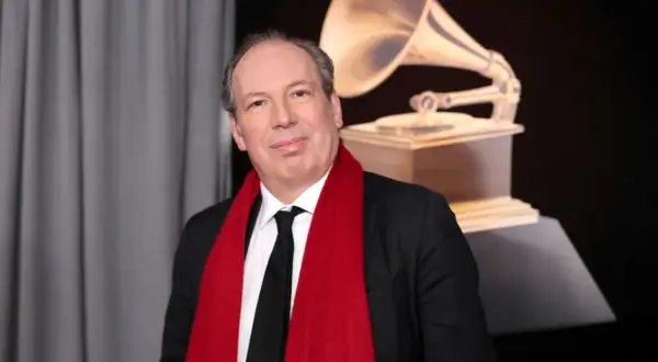 Hans Zimmer, który napisał muzykę do filmu Gladiator, pozuje z czerwoną szarfą i statuetką Grammy.