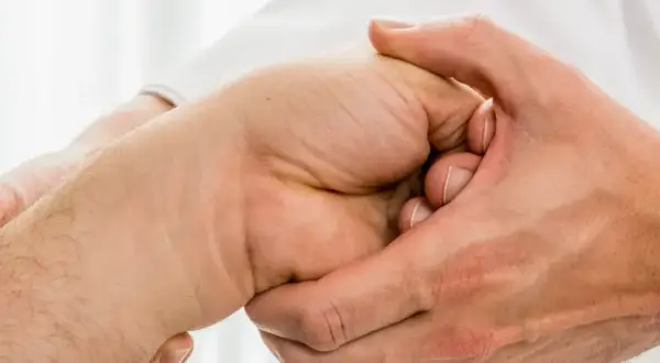 Arzt untersucht Hand, tastet den Os lunatum ab.