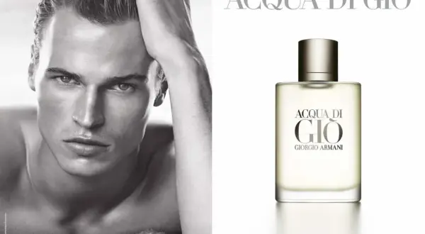 Mężczyzna z dłonią na głowie obok flakonu perfum Acqua di Gio Pour Homme Giorgio Armani.