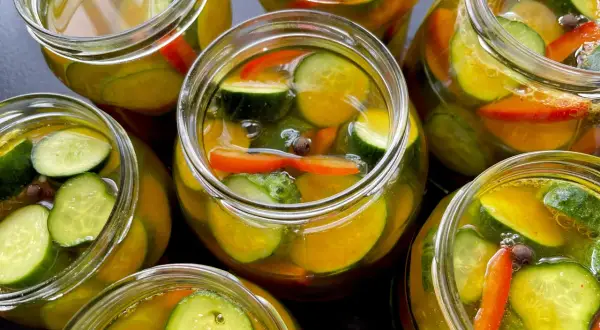 Słoiki pełne chrupiących ogórków z papryką i przyprawami, gotowe na zimę. Te ogórki w curry zachwycą smakiem!