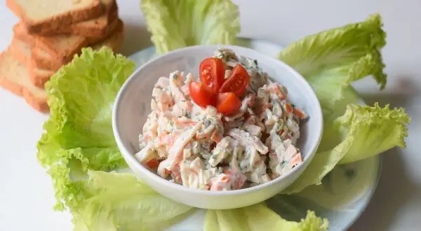 Deliciosa ensalada de cangrejo cremosa, servida con hojas de lechuga fresca y tostadas.