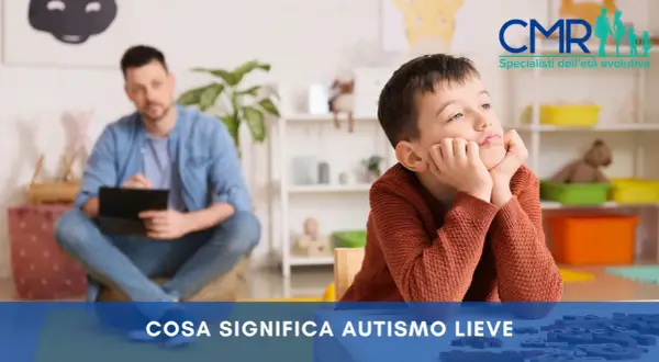 Bambino pensieroso in terapia, con un uomo sullo sfondo. Si parla di autismo lieve e della sua percentuale di invalidità.