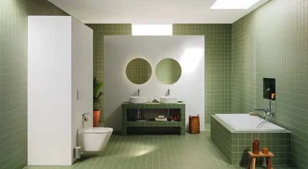 Moderno baño con azulejos verdes, doble lavabo, bañera y WC. Un espacio ideal para renovar el baño con estilo y funcionalidad.