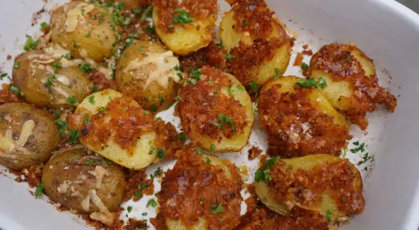 Knusprige parmesan kartoffeln mit Petersilie und grobem Salz bestreut, bereit zum Genießen.