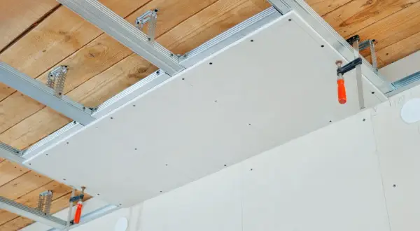 Structure métallique pour un double plafond en cours d'installation, avec des plaques de plâtre fixées.