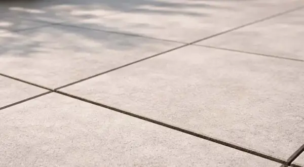 Pavimentazione esterna con piastrelle grigie e fughe scure, perfette per un terrazzo moderno. Il cemento per fughe esterne garantisce durata e stile.