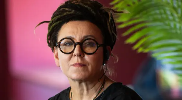 Olga Tokarczuk, wiek nieznany, w okularach i z dredami, słucha uważnie.