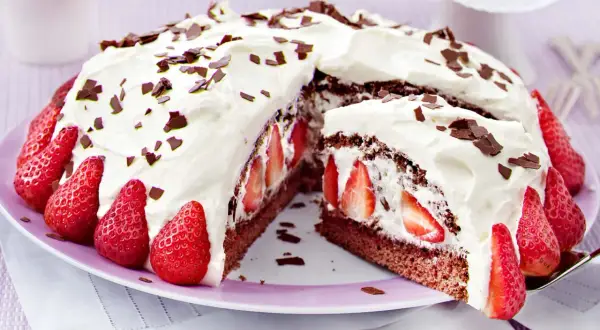 Saftige Stracciatella Torte mit frischen Erdbeeren und Schokostückchen, üppig mit Sahne verziert.