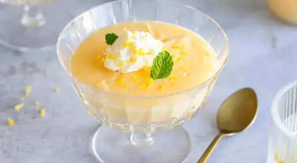 Cremiges Lemon Curd Dessert im Glas, garniert mit Sahne, Minze und Zitronenschale. Perfekt für ein einfaches Lemon Curd Rezept.
