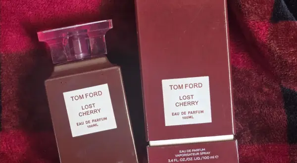 Elegancki flakon i pudełko perfum Tom Ford Lost Cherry 100 ml na tle czerwonego, miękkiego materiału.