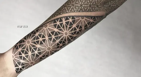 Geometryczny tatuaż dotwork na przedramieniu, tworzący hipnotyzujący wzór z trójkątów i kropek.