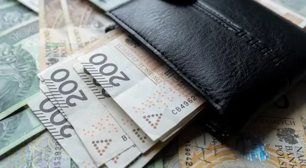 Czarny portfel na stosie polskich banknotów 200 zł. Czy to wystarczy na minimalne wynagrodzenie?