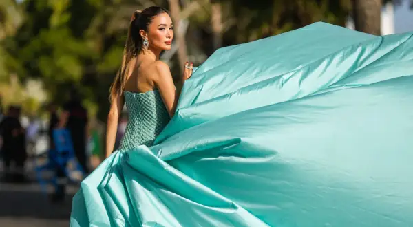 Elegante Dame im mintgrünen Ballkleid, perfekt für einen "black tie optional" Anlass. Ihr Kleid weht im Wind.