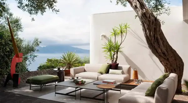 Arredamento moderno su un terrazzo scoperto con vista mare. Divani, tavolini e pouf creano un'oasi di relax, un'idea per come coprire un terrazzo scoperto con stile.