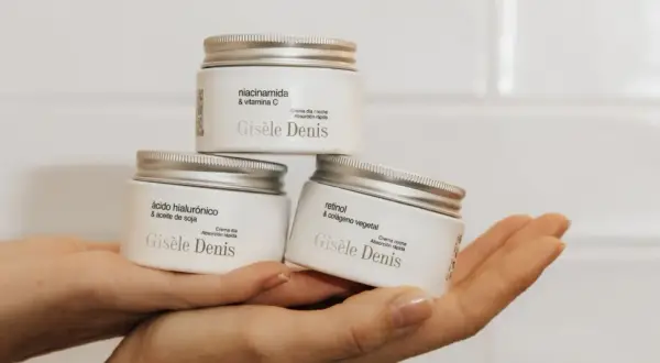 Hände halten drei Gisele Denis Cremetiegel: einer mit Niacinamid & Vitamin C, einer mit Hyaluronsäure & Sojaöl, und einer mit Retinol & pflanzlichem Kollagen.