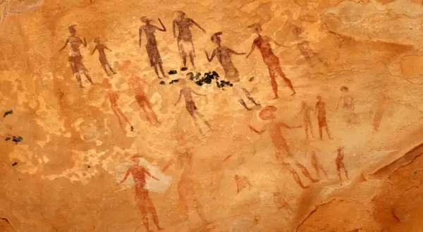 Prehistoryczne malarstwo jaskiniowe ukazuje grupę postaci ludzkich w ruchu, być może podczas rytuału lub polowania.
