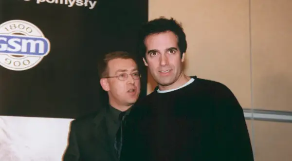 David Copperfield, w czarnym swetrze, stoi obok mężczyzny w garniturze.