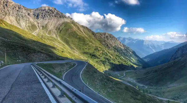 Kręta, górska stelvio droga wije się przez zielone zbocza Alp, prowadząc w głąb doliny.