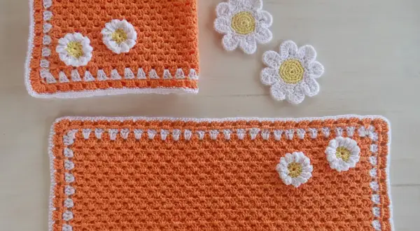 Tovagliette uncinetto schemi gratis: un set arancione con fiori bianchi e gialli, perfetto per decorare la tavola.