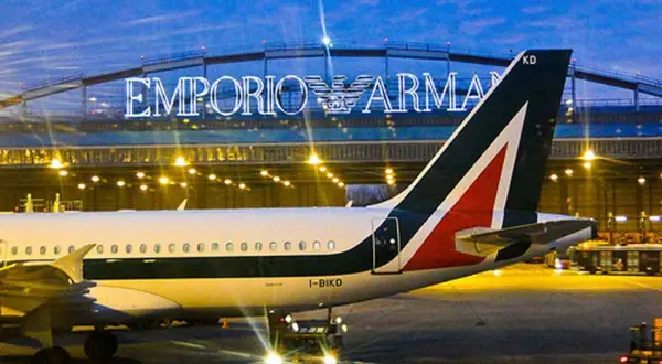 Samolot Alitalia na lotnisku w Mediolanie, w tle podświetlony napis Emporio Armani.