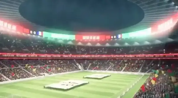 Widok na wypełniony po brzegi stadion, największy stadion na świecie, z flagami i tablicą wyników.