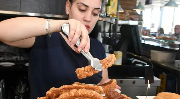 Camarera sirviendo crujiente chicharrón, perfecto para comer en carretera cerca de Zaragoza.