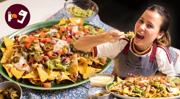 Una mujer disfruta de unos deliciosos nachos tex mex, cargados de carne, guacamole, queso y jalapeños.